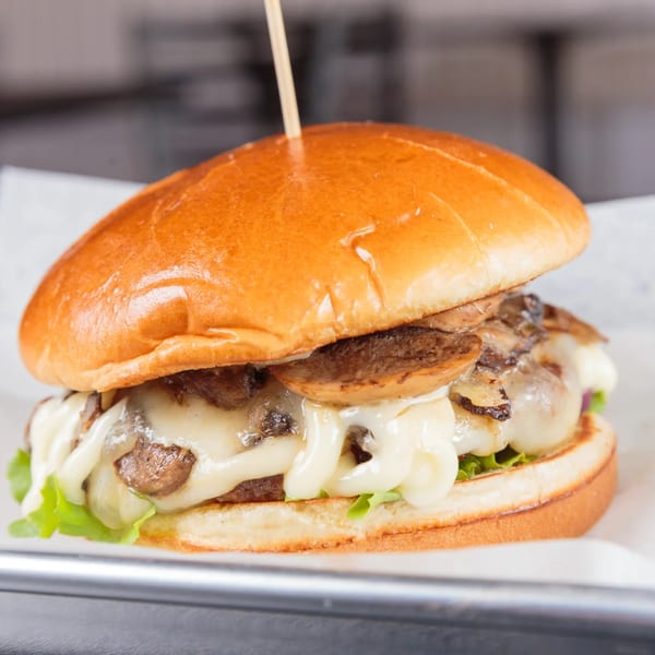 A mushroom swiss burger from The Burger Life with melted cheese, sautéed mushrooms, and lettuce.
