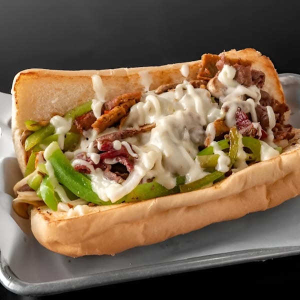 A Philly cheesesteak sandwich with steak, green peppers, onions, and melted cheese on a hoagie roll.